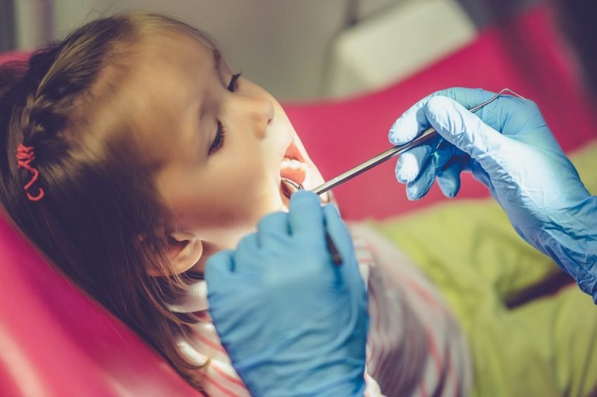 dentist-examining-little-girl-her-office-min